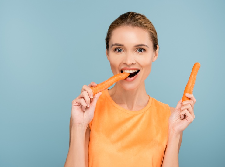 donna mangia carote arancione 